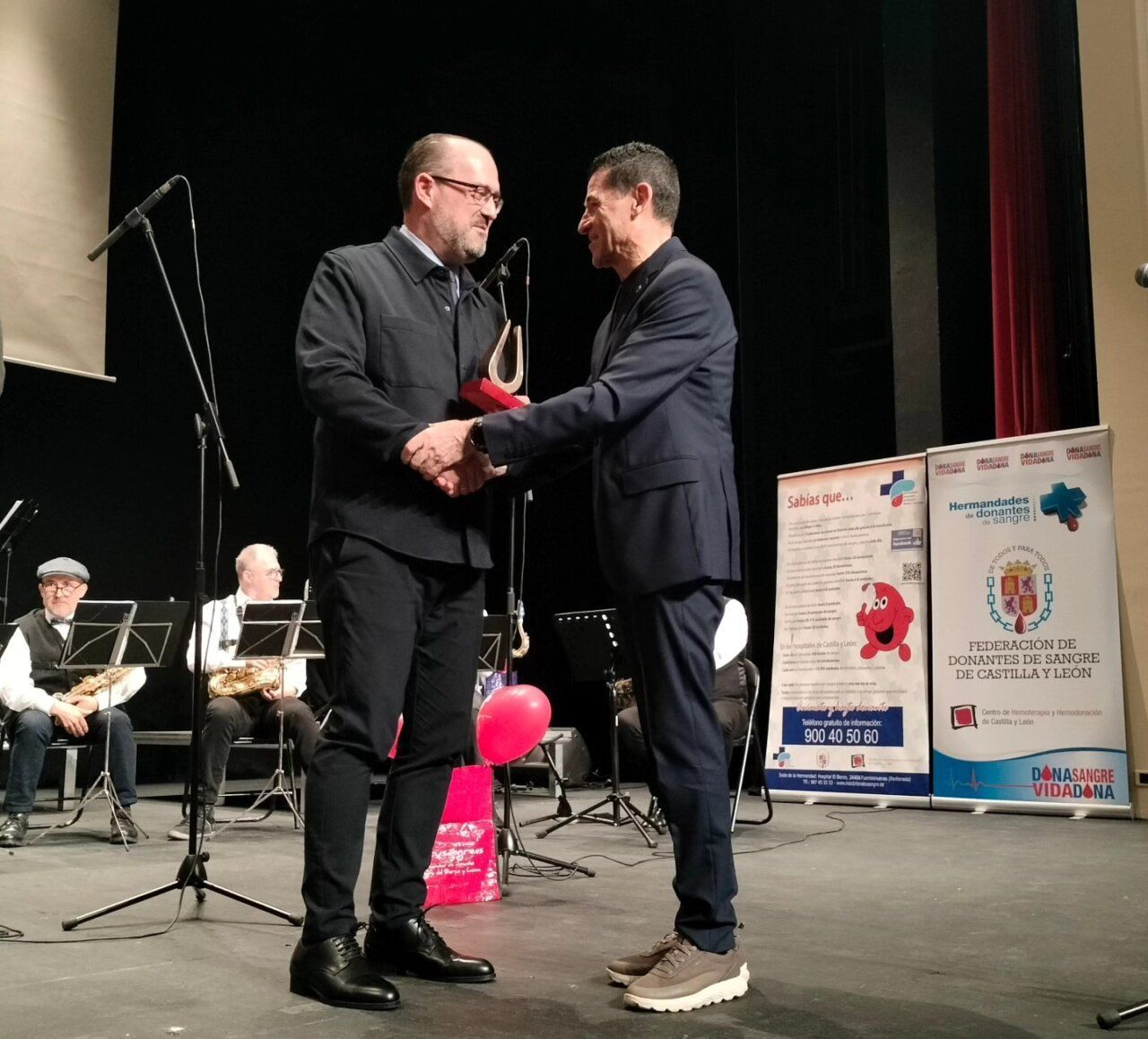 Dos hombres intercambiando un premio en un evento de donación de sangre