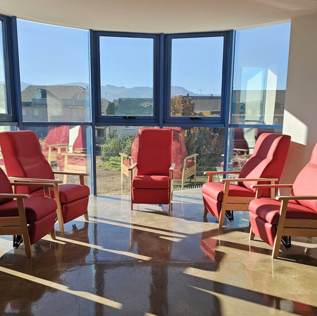 Sala luminosa con sillones rojos en el Centro de Día AFA Bierzo