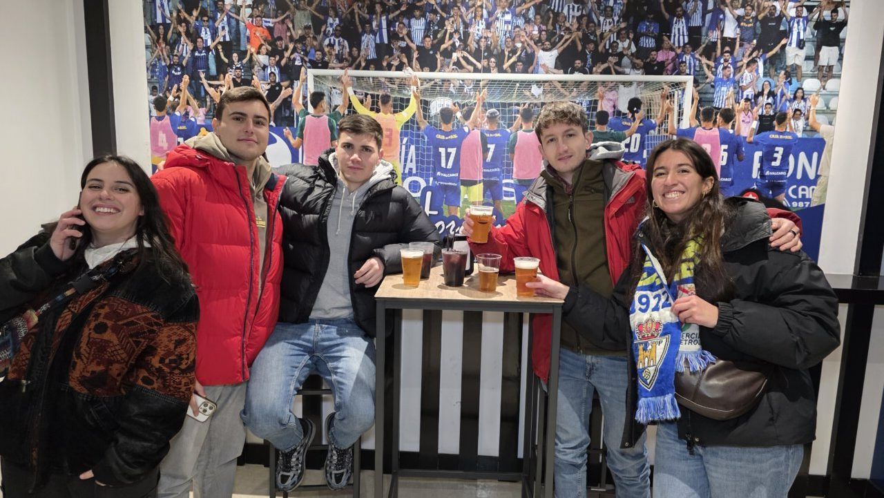 Grupo de amigos disfrutando de una bebida en un bar deportivo