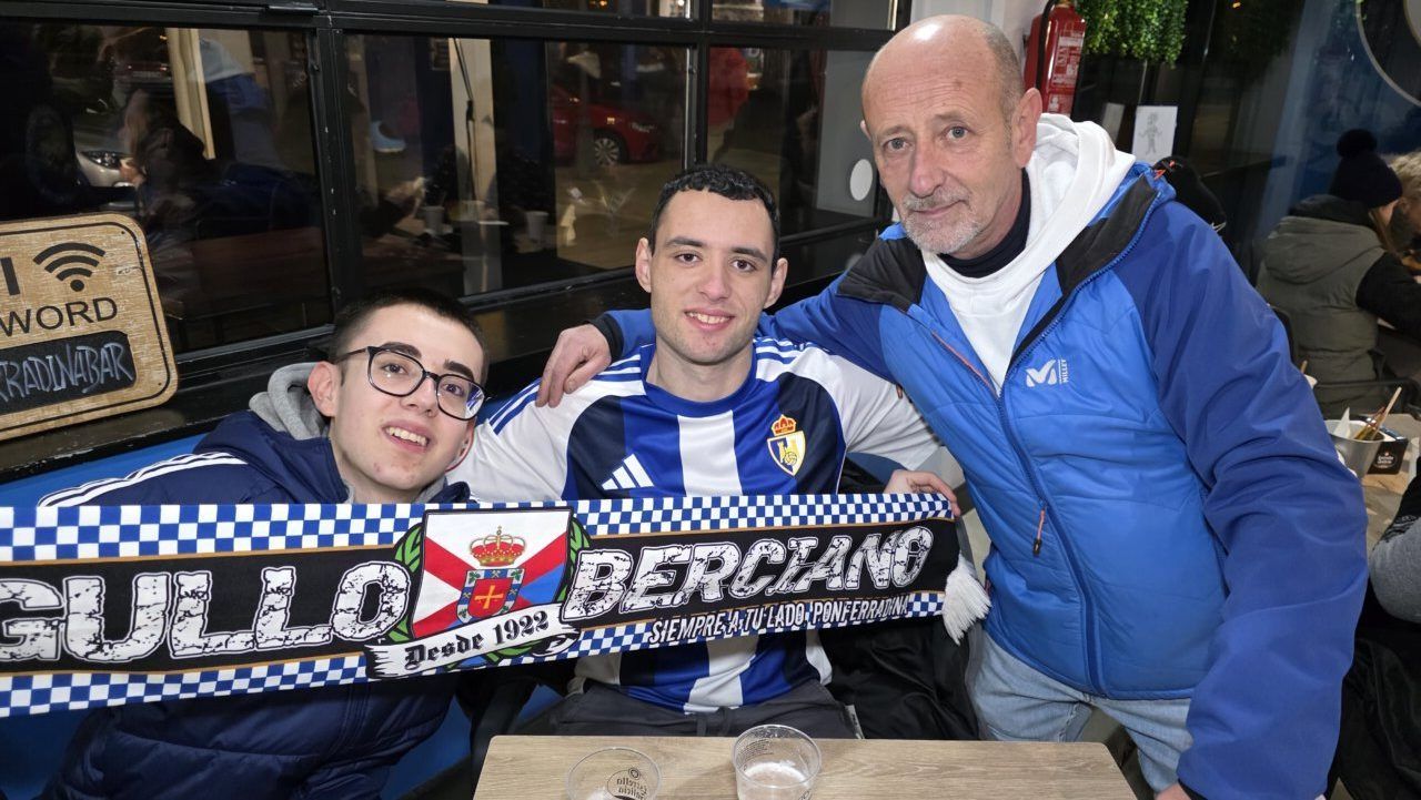 Tres aficionados posando con bufandas del equipo de fútbol Ponferradina