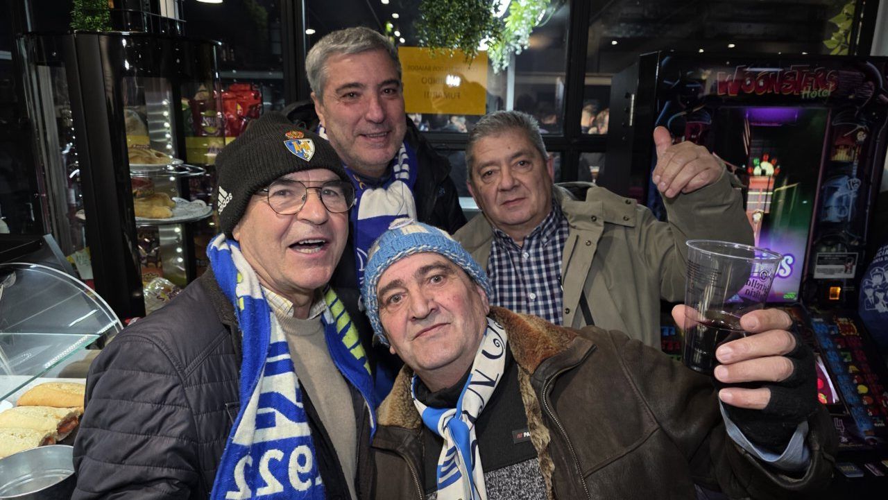 Grupo de aficionados celebrando en un bar con bufandas del equipo