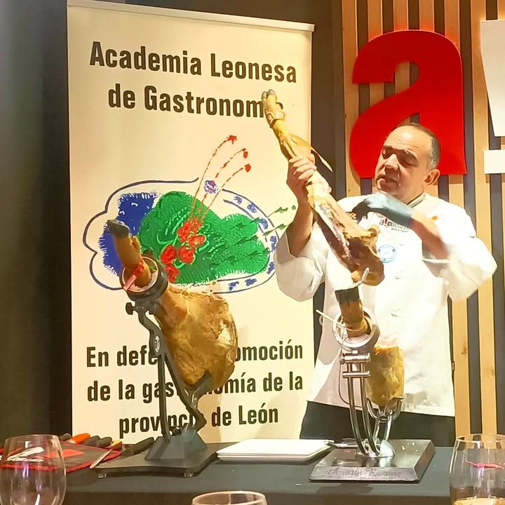 Agustín Risueño cortando jamón en un evento gastronómico en León.