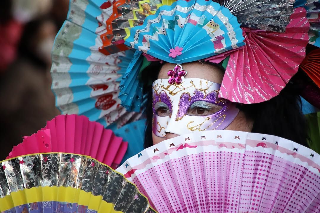 Persona con máscara y abanicos coloridos en el Carnaval de León