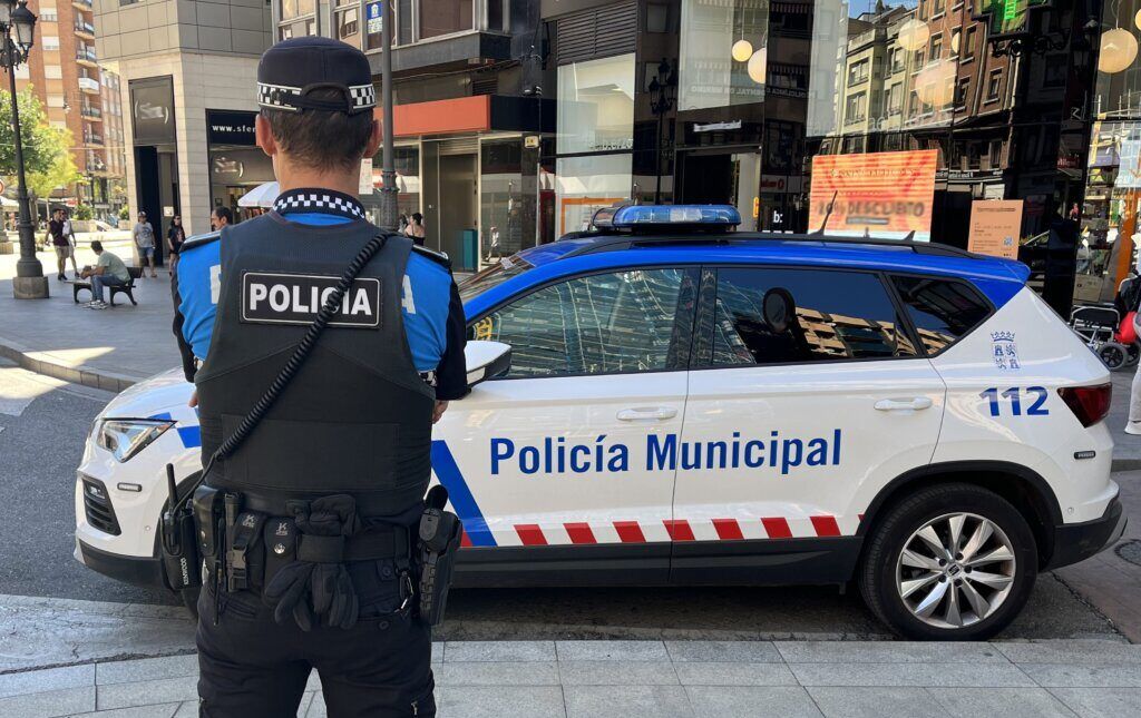 Agente de la Policía Municipal junto a un vehículo patrulla en la ciudad.