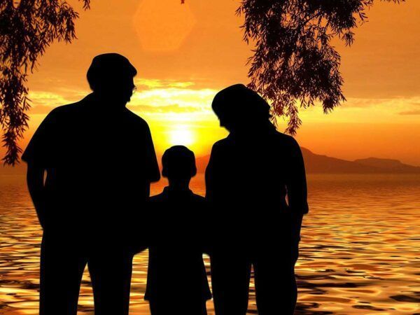 Siluetas de una familia en un atardecer junto al agua