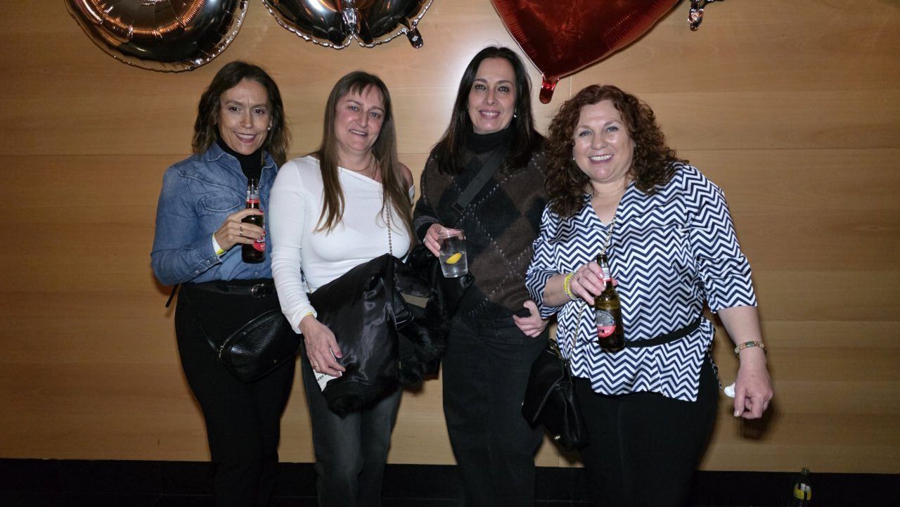 Cuatro mujeres posando en una fiesta con bebidas en mano