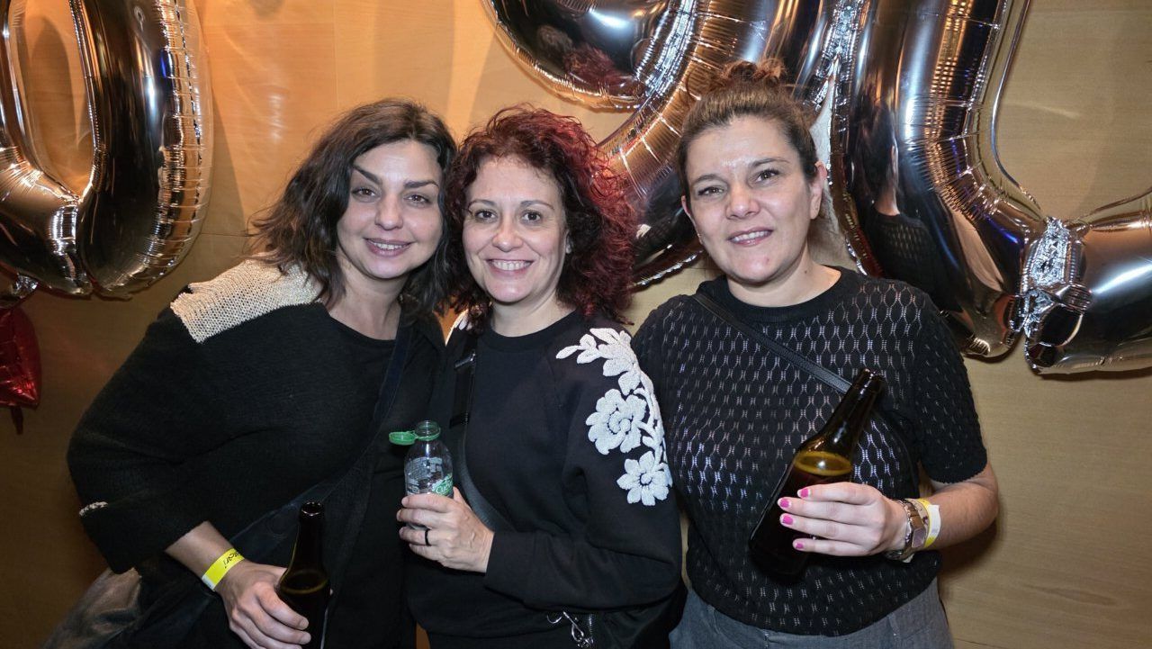 Tres mujeres sonrientes en una fiesta temática de los años 80 y 90