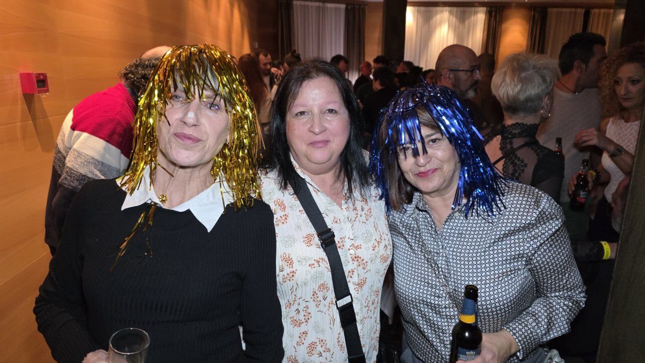 Tres mujeres con pelucas brillantes en una fiesta temática de los 80 y 90.