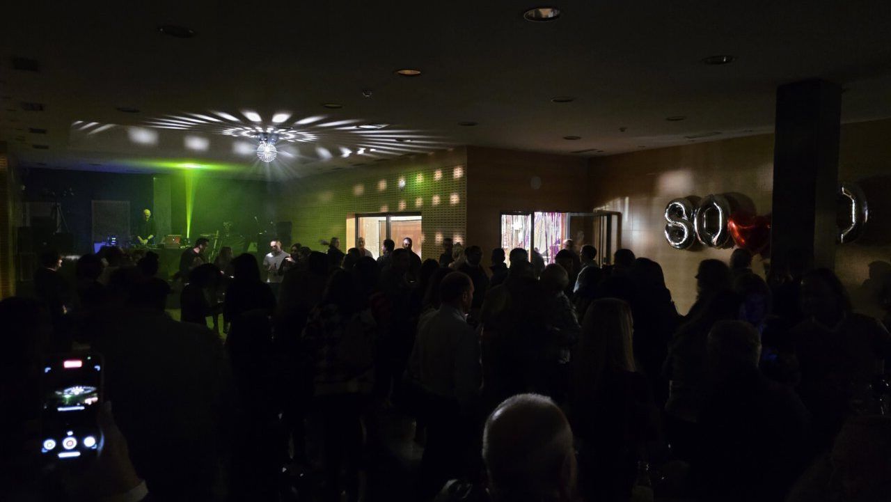 Fiesta temática de los años 80 y 90 en un casino con luces y gente bailando.