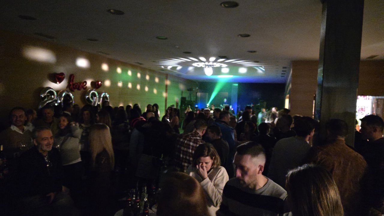 Multitud de personas disfrutando en una fiesta temática de los años 80 y 90.
