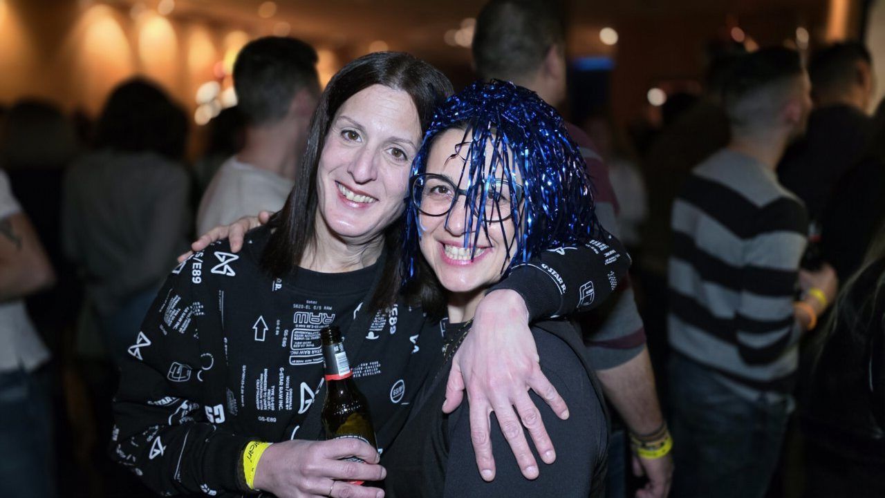 Dos mujeres sonriendo en una fiesta con decoraciones brillantes