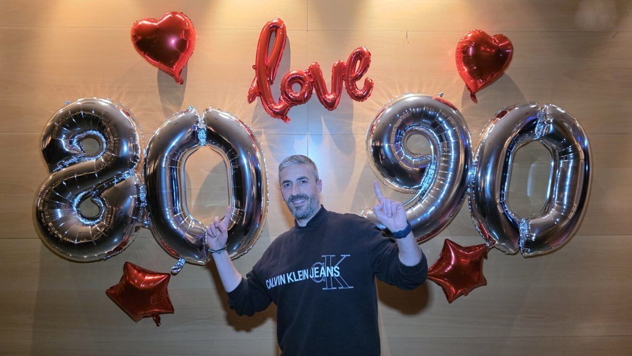 Hombre posando con globos de los años 80 y 90 en fiesta temática