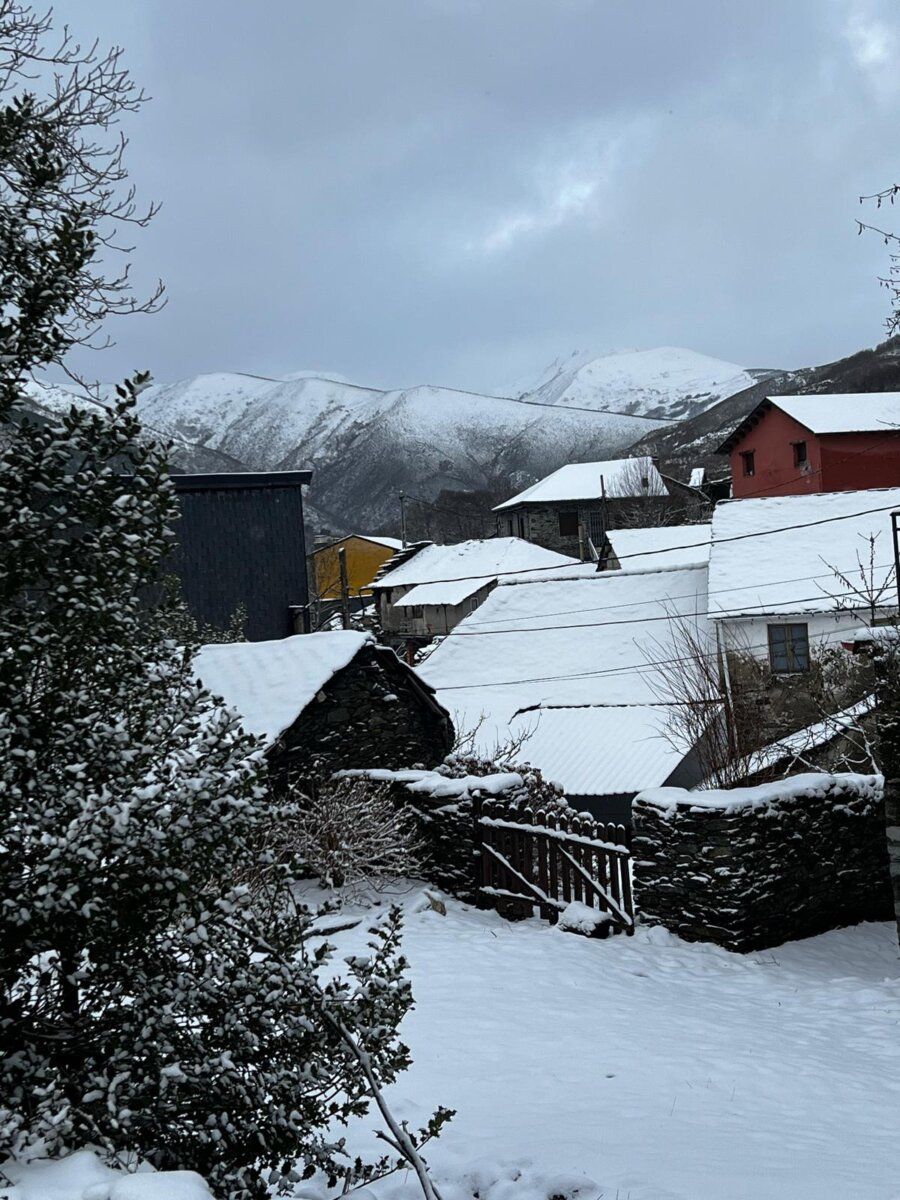Vista de Fornela cubierta de nieve con montañas al fondo