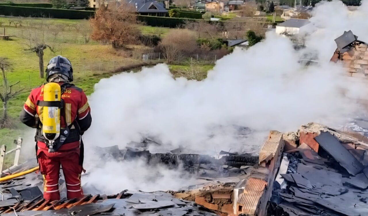 Bombero controlando un incendio en la cubierta de una vivienda en Molinaseca