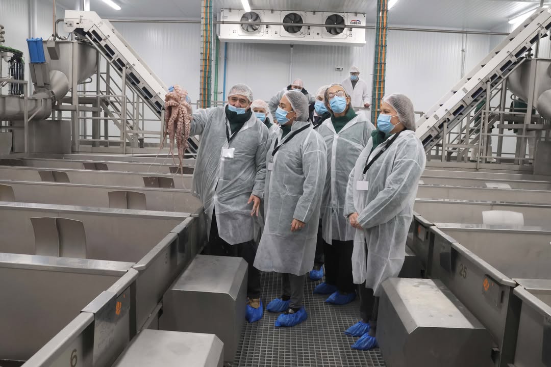 Grupo de personas en instalaciones de acuicultura sosteniendo un pulpo