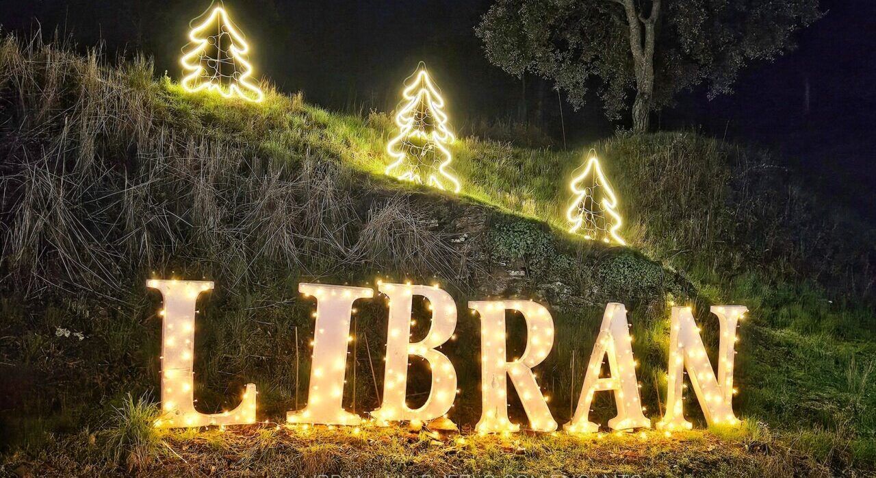Cartel iluminado de Librán con árboles navideños de fondo