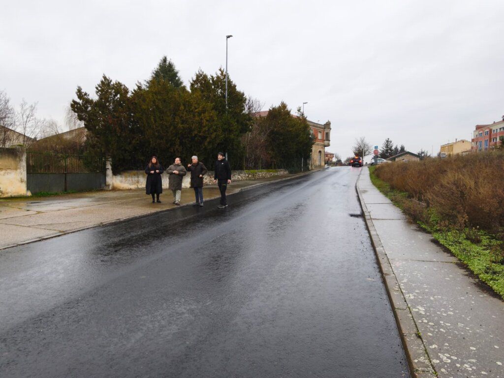 Mejora del firme en la carretera LE-114 en La Bañeza con personas observando