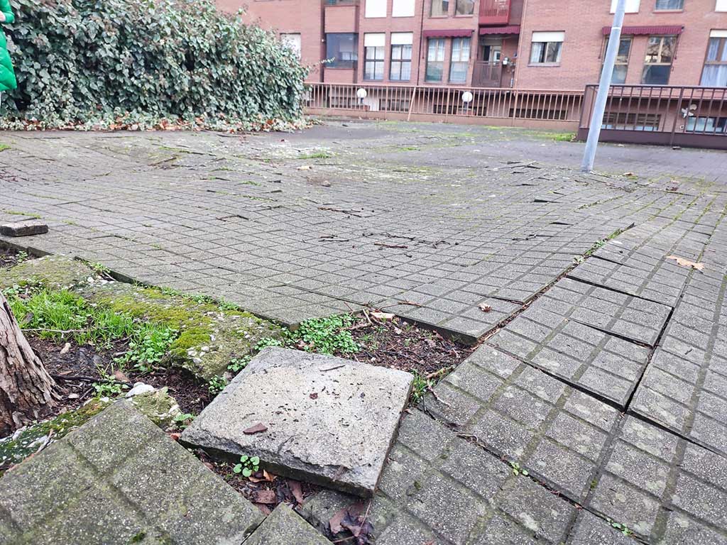 Pavimento deteriorado en una zona urbana con baldosas levantadas
