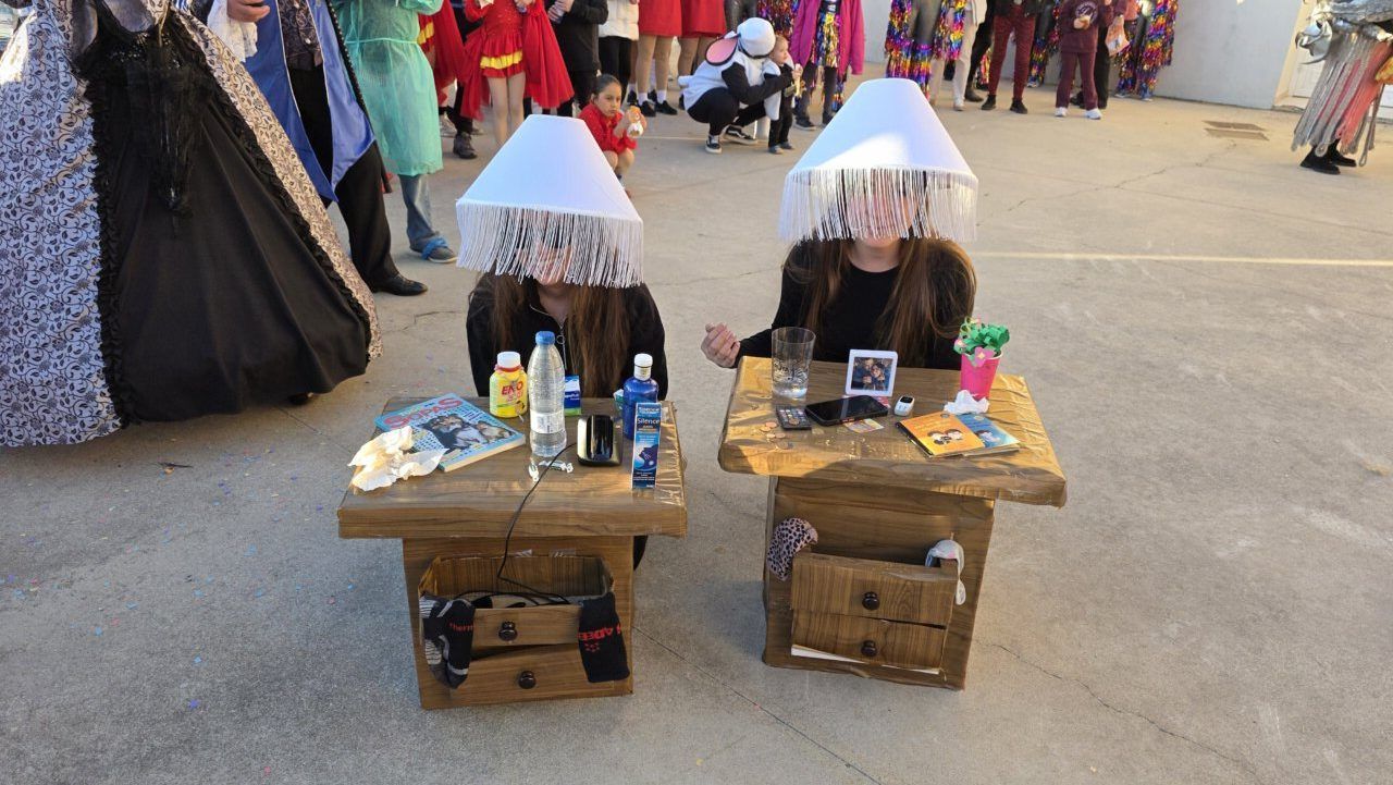 Dos personas disfrazadas en el carnaval de Arganza con mesas decoradas