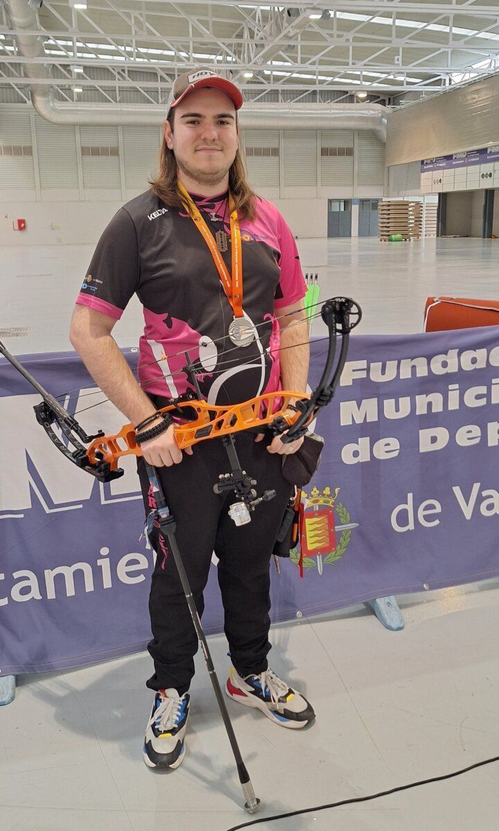 Héctor González sosteniendo un arco con medalla en campeonato de tiro con arco