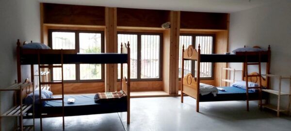 Interior del albergue Montes de Valdueza con literas y ventanas grandes