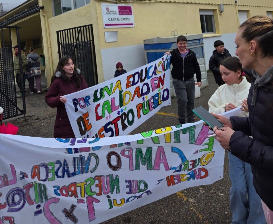 Concentración de AMPAs en un centro educativo con pancartas coloridas.