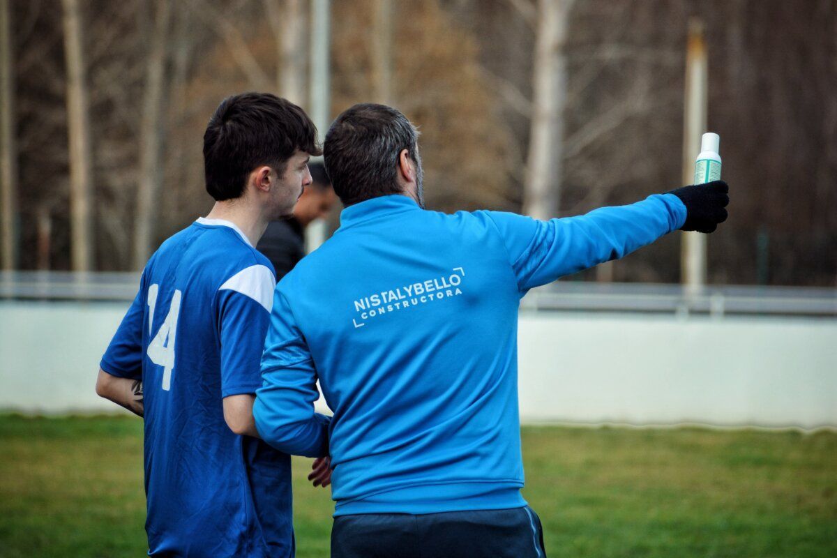 Entrenador dando instrucciones a un jugador durante un partido de fútbol