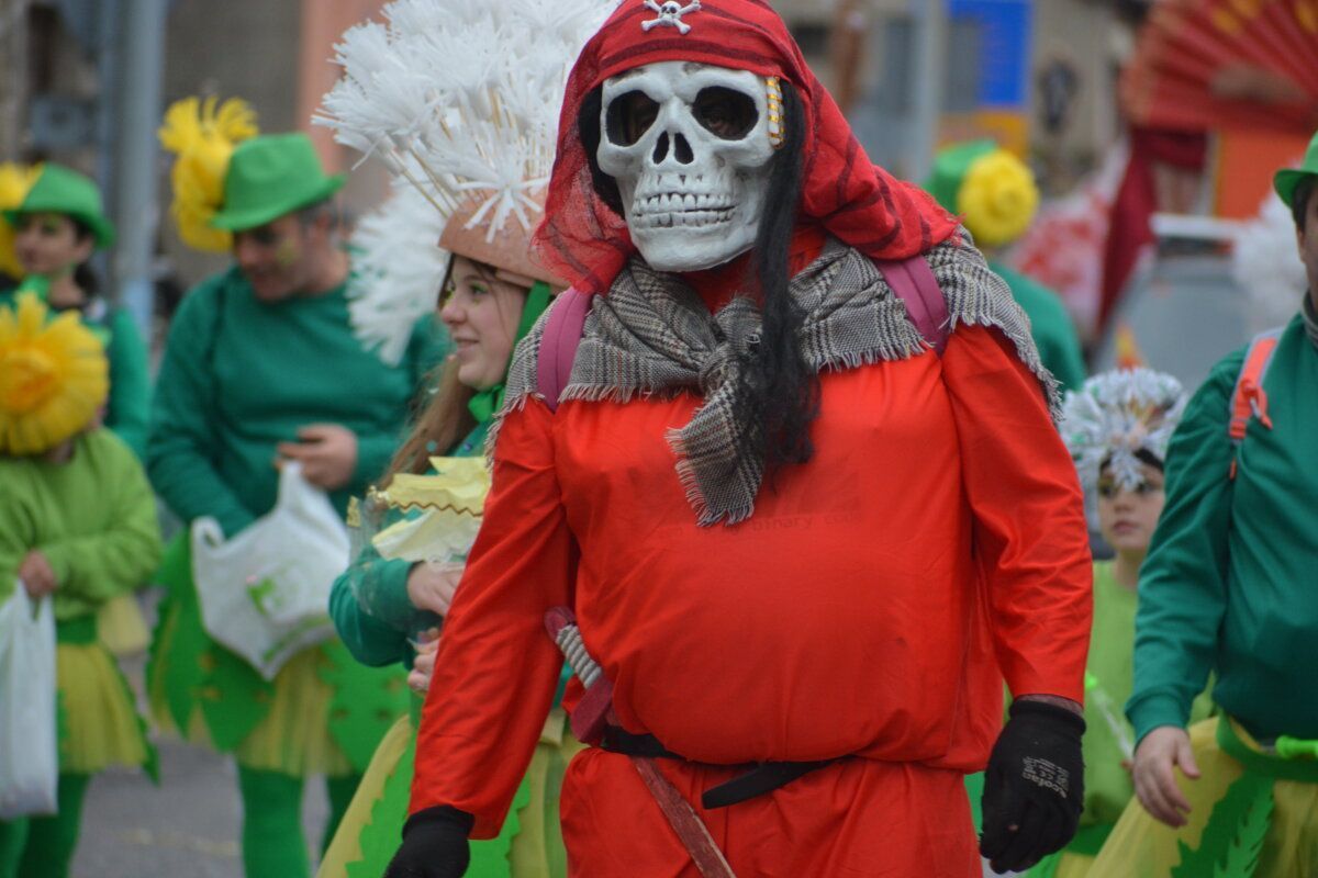 Personaje de carnaval con disfraz de esqueleto y otros participantes