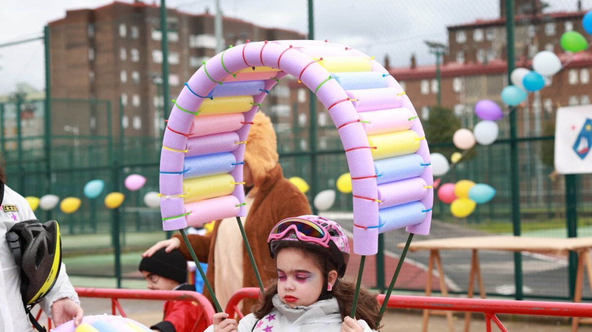 Niña con maquillaje y gorra sosteniendo un arco de espuma en el carnaval
