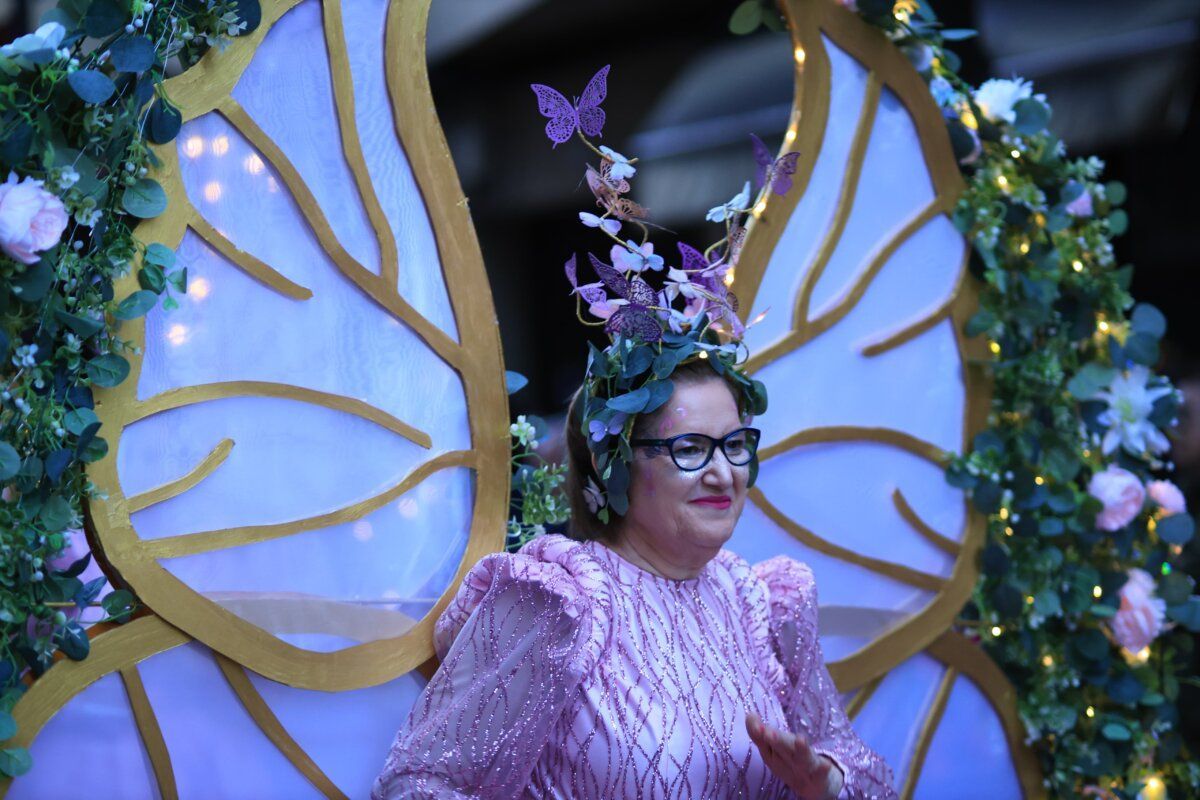 Mujer con vestido rosa y corona de flores en desfile de carnaval
