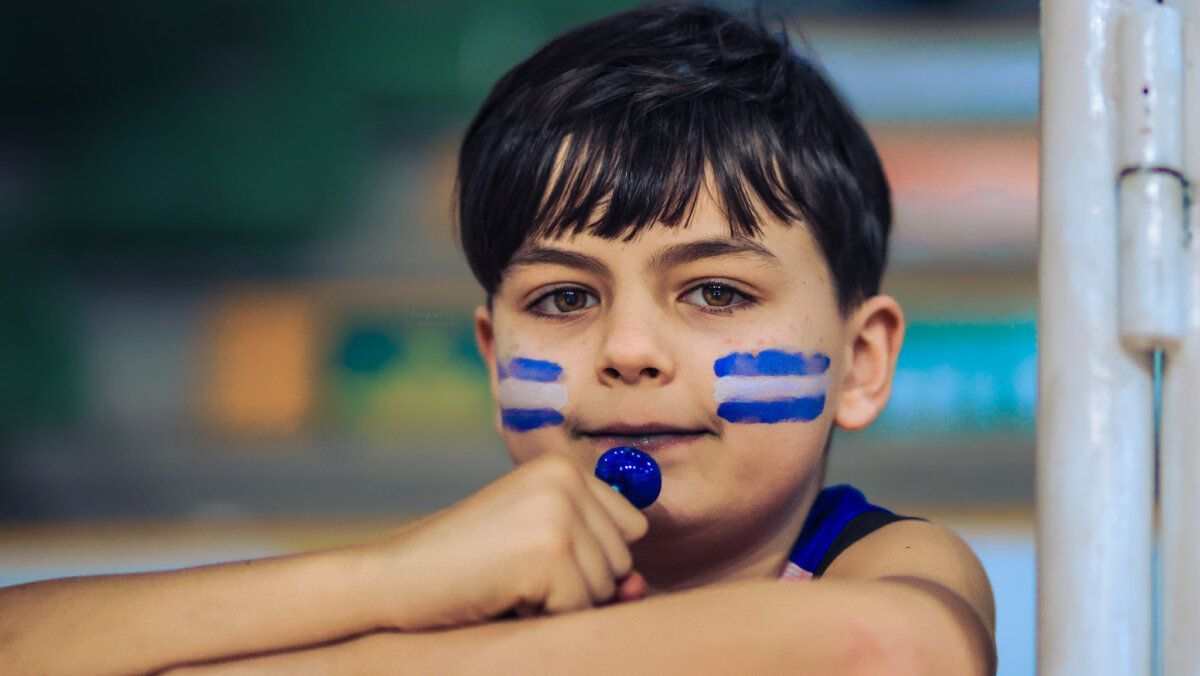 Niño con pintura facial azul y blanca en un evento deportivo