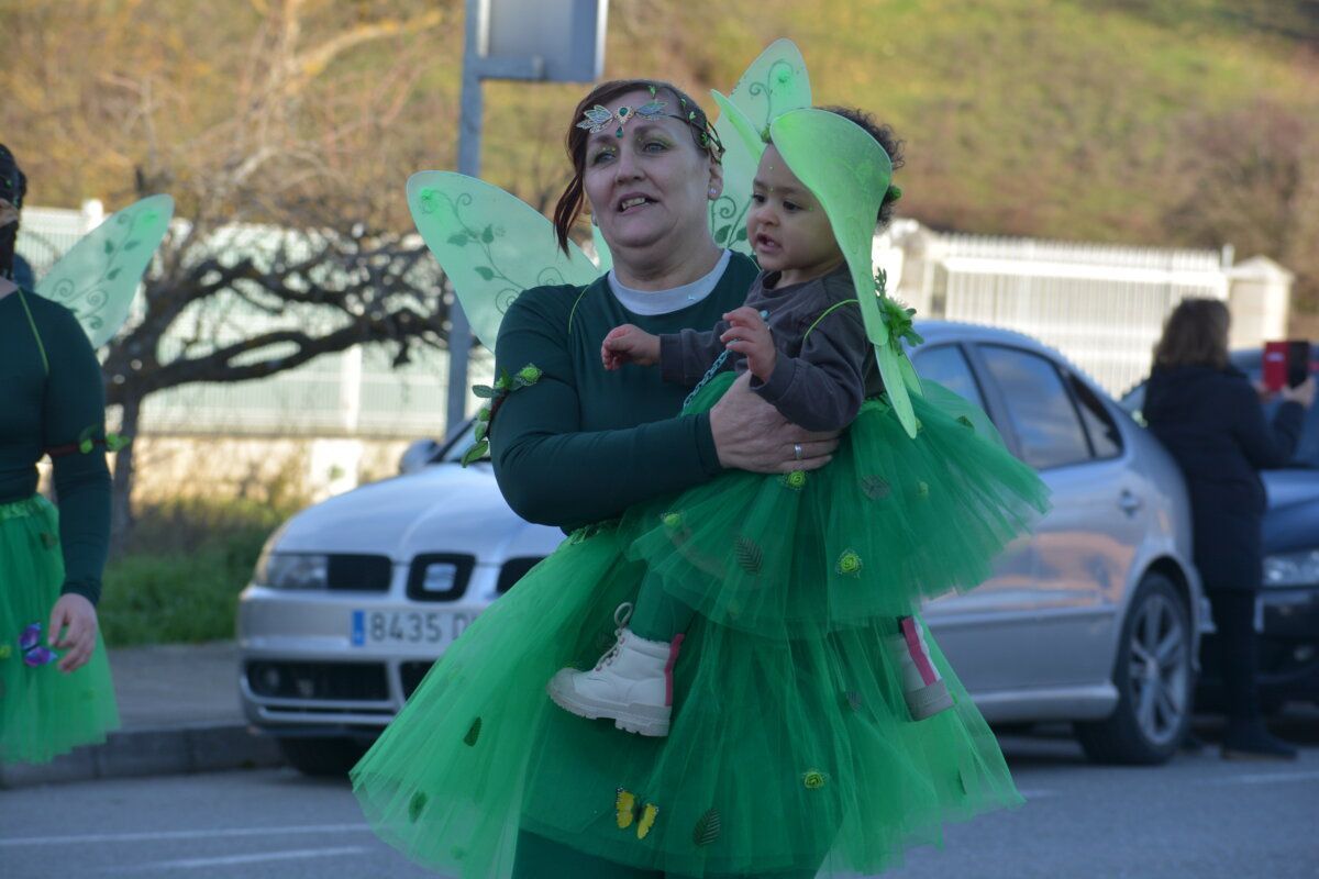 Mujer con disfraz de hada sosteniendo a un niño en un desfile de carnaval