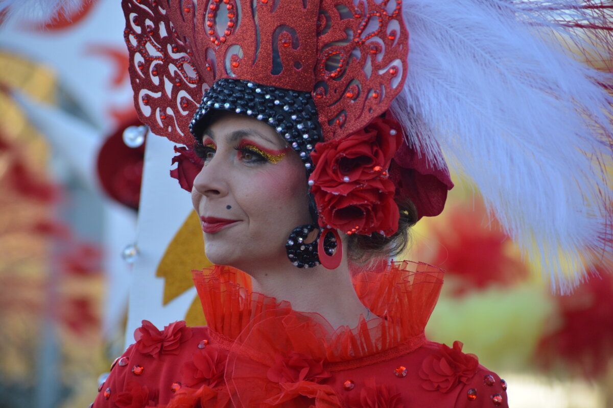 Mujer con disfraz rojo y plumas en desfile de Carnaval en Cacabelos