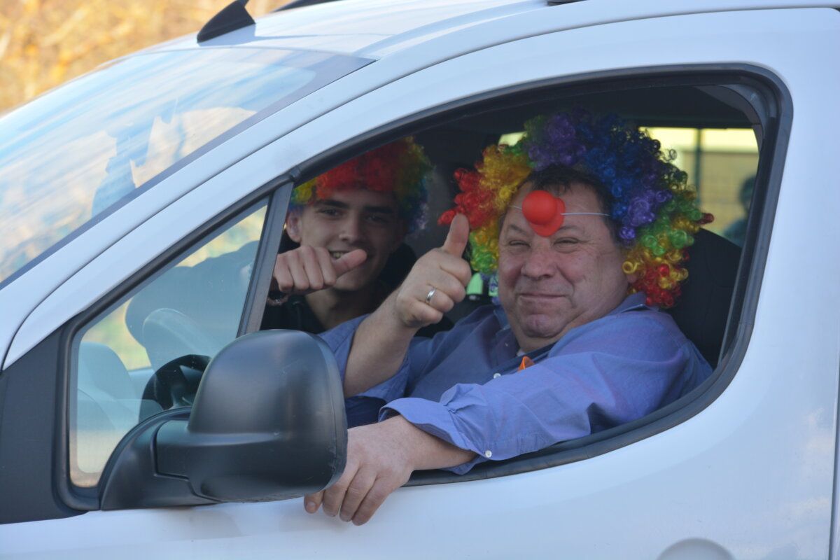 Hombres con pelucas de colores en un coche durante el desfile de carnaval