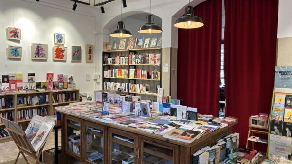 Vista interior de una librería con libros y arte en las paredes