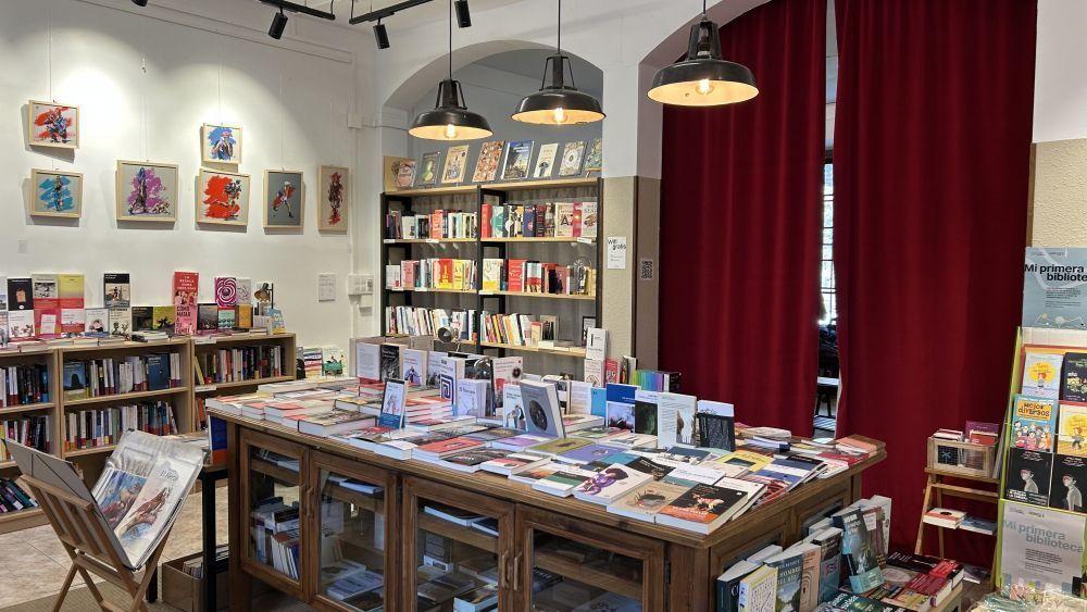 Vista interior de una librería con libros y arte en las paredes