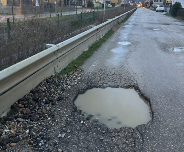 Calzada deteriorada con baches y agua estancada en Ponferrada