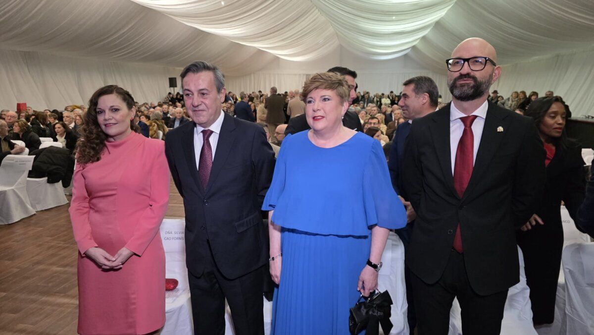 Cuatro personas posando en un evento con público al fondo