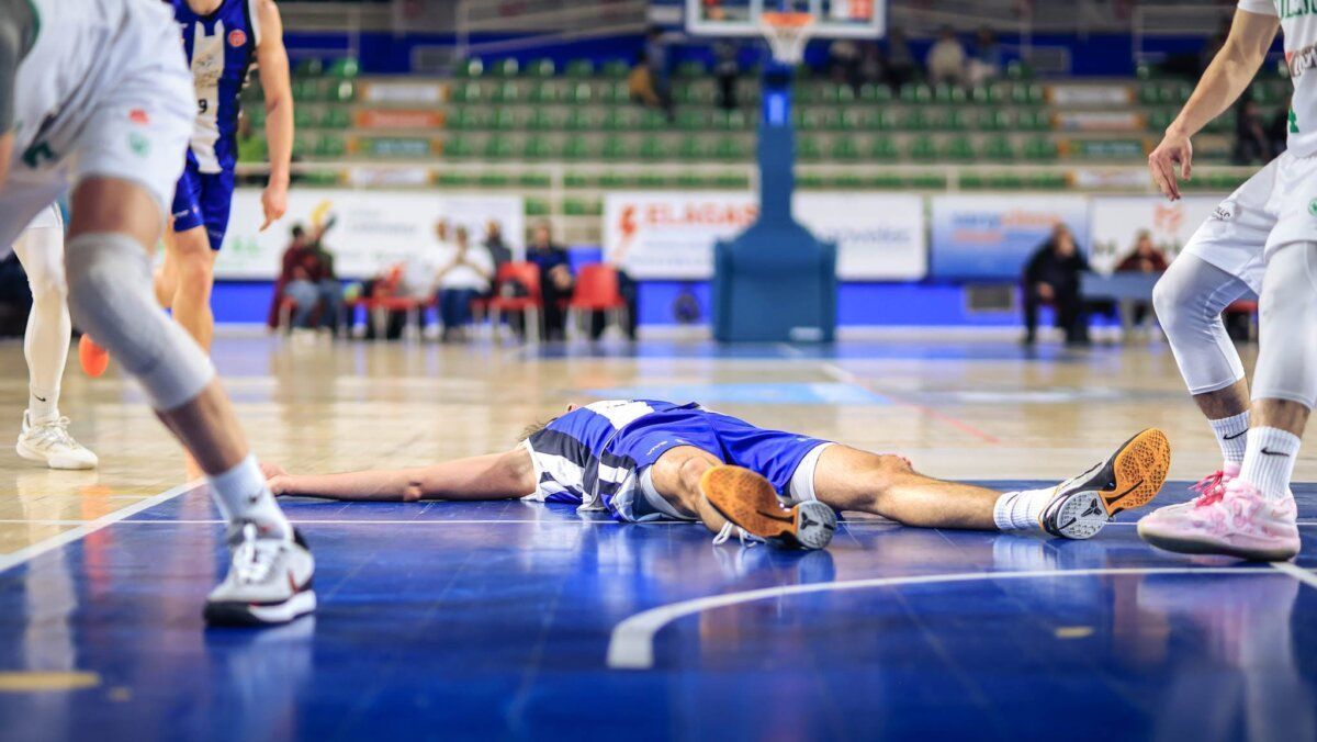 Jugador de baloncesto caído en la cancha durante un partido.