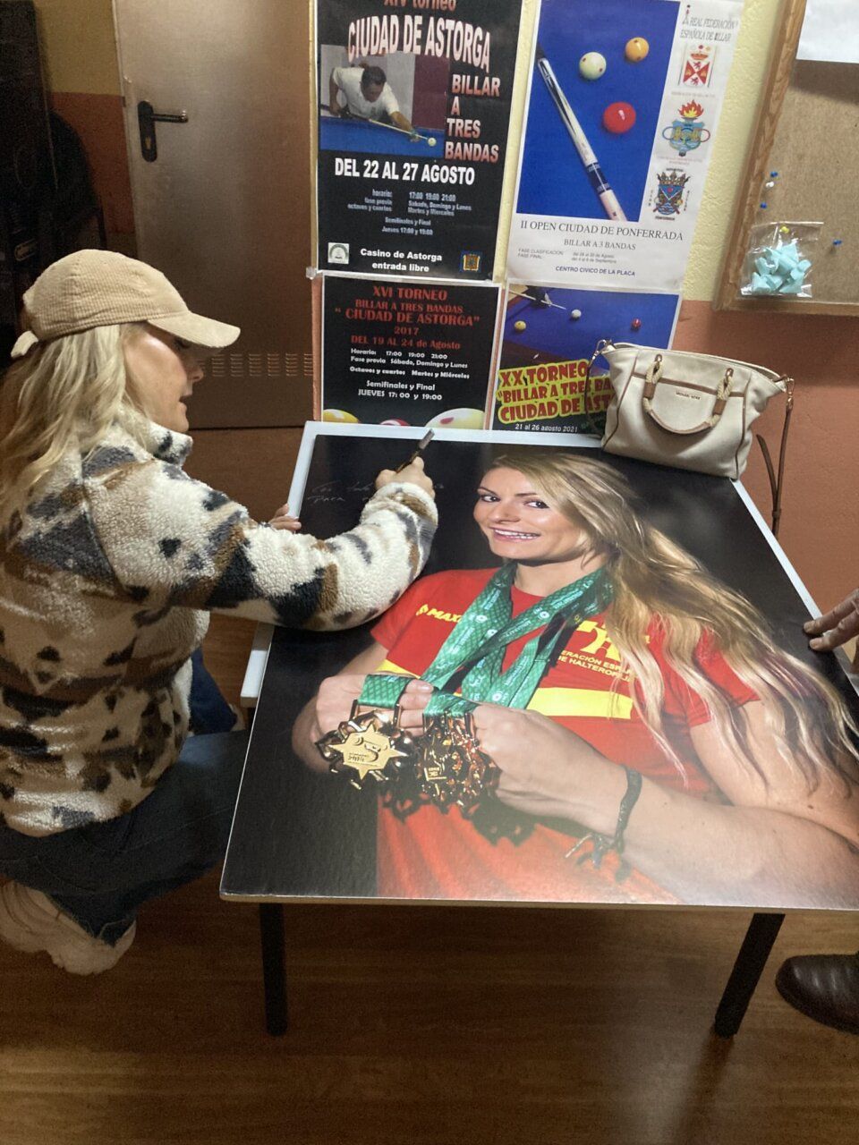 Lidia Valentín firmando una foto con medallas en el Club Billar Ponferrada