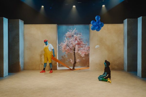 Escena de la obra Thauma con actores y un árbol de flores