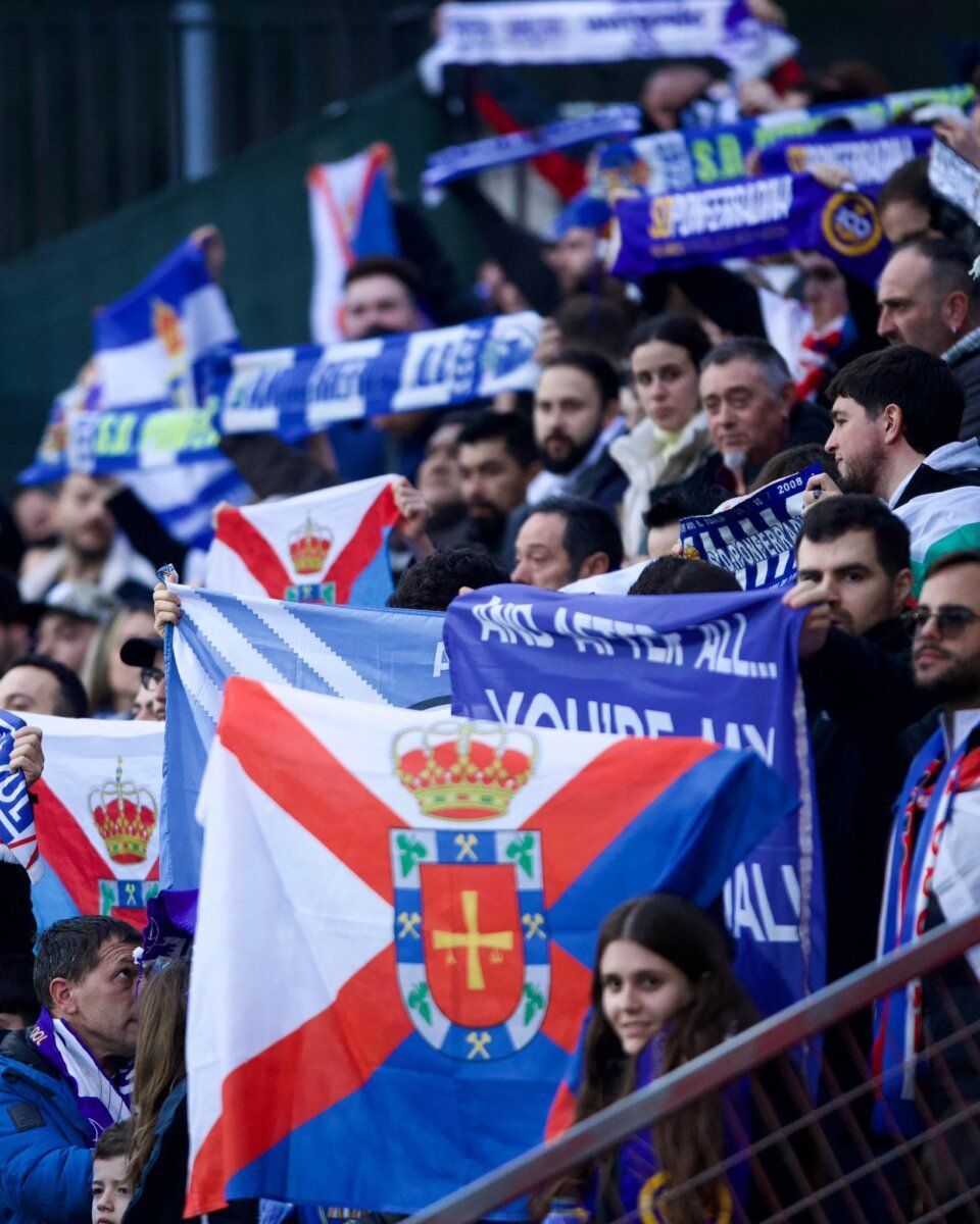 Aficionados sosteniendo banderas en el estadio durante el partido