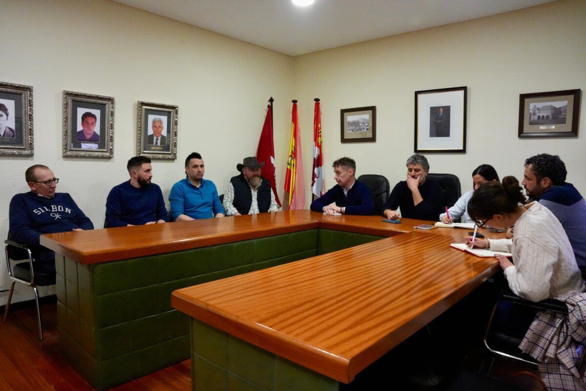 Reunión de ganaderos en una sala con mesa y banderas
