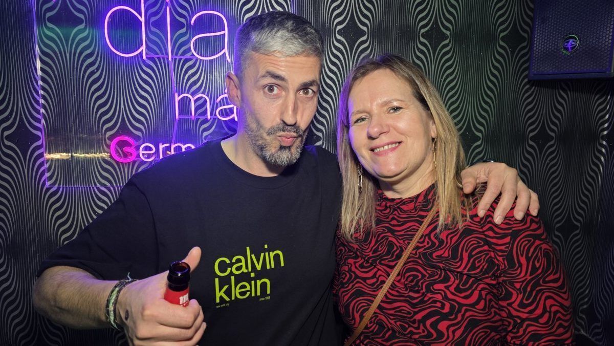 Dos personas posando en una fiesta con fondo iluminado