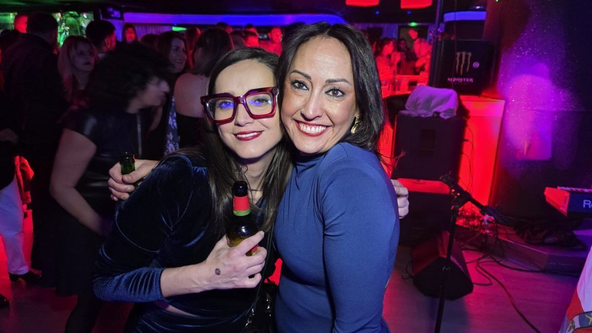 Dos mujeres sonrientes en una fiesta con luces de colores