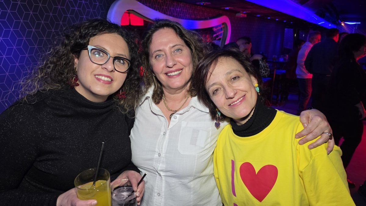 Tres mujeres sonriendo en una fiesta con bebidas en mano