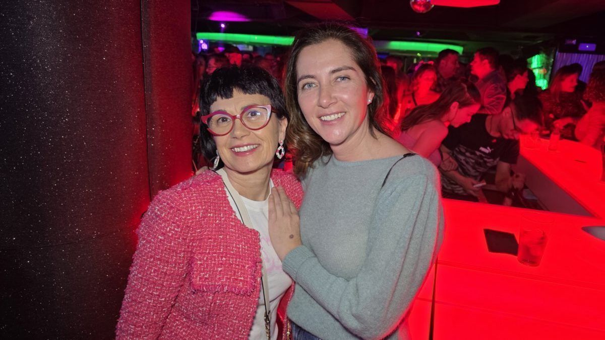 Dos mujeres sonrientes en una fiesta con luces de colores