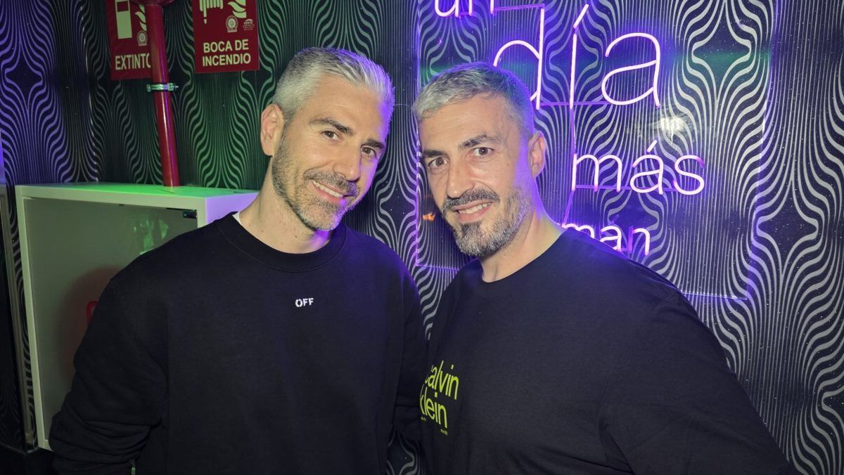 Dos hombres sonriendo en un ambiente festivo con luces de neón