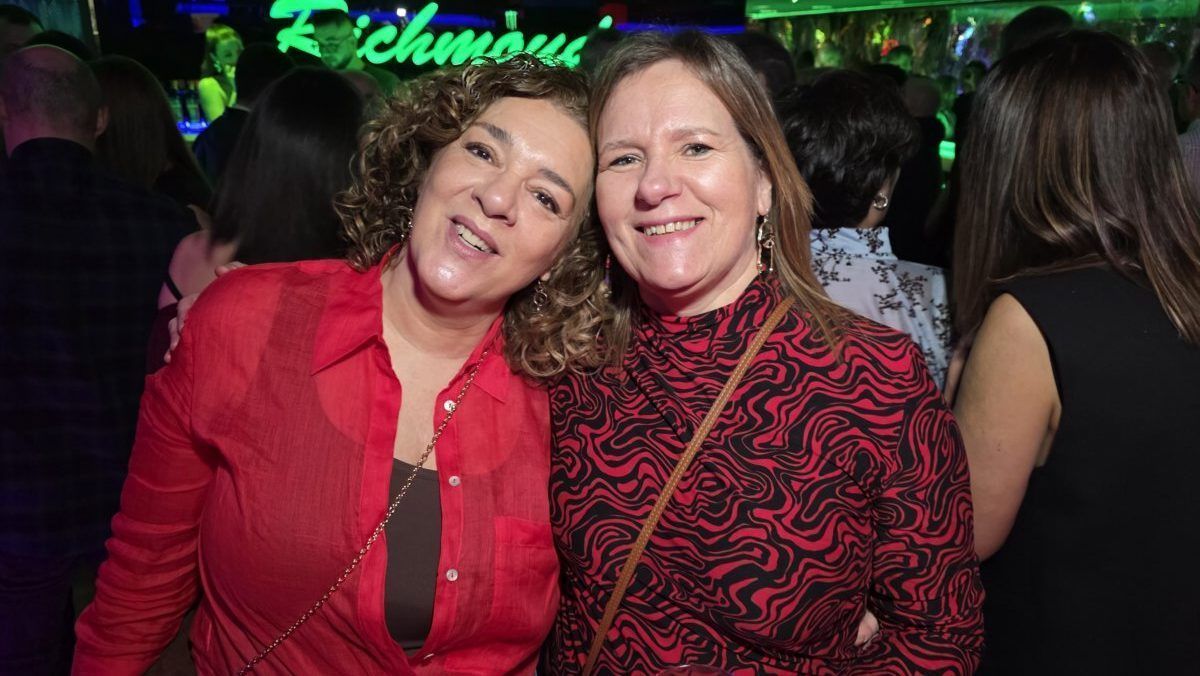 Dos mujeres sonrientes en una fiesta en Richmond, con luces de fondo