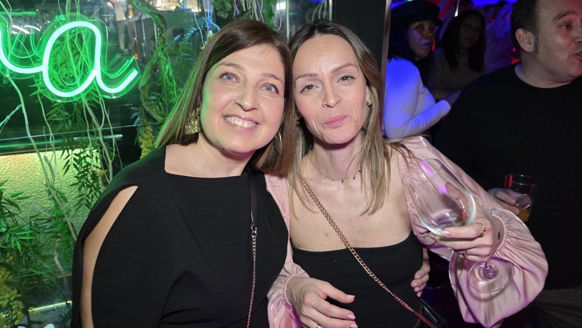 Dos mujeres sonrientes en una fiesta con luces de colores